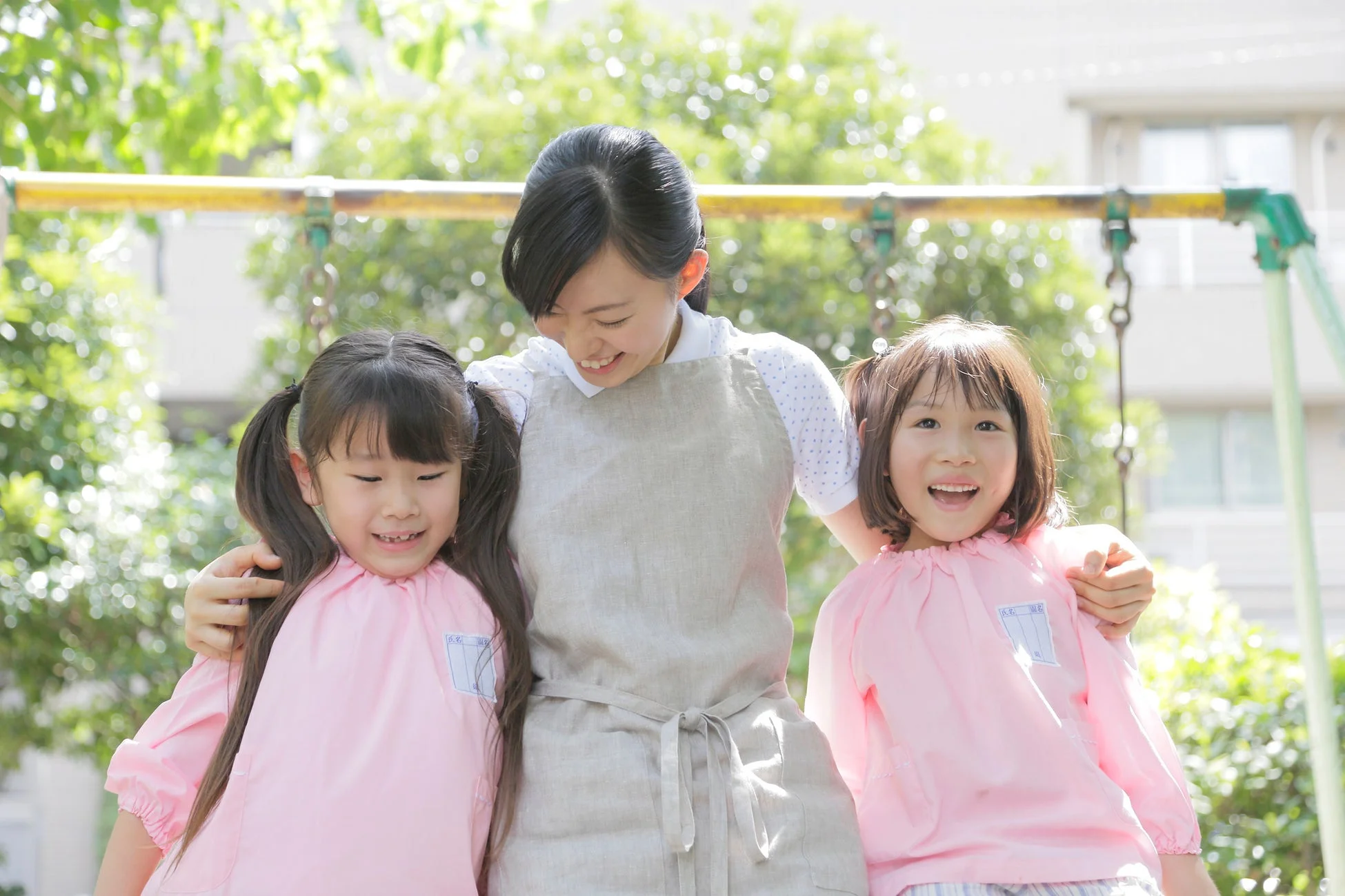 保育士と園児が笑顔で抱き合う様子