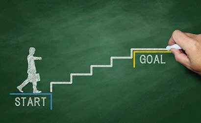 黒板にチョークで描かれた人物が「START」から階段を上り、「GOAL」に向かって進む様子。
