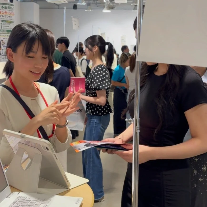 イベント会場で、女性スタッフが来場者とタブレットを使って交流している様子