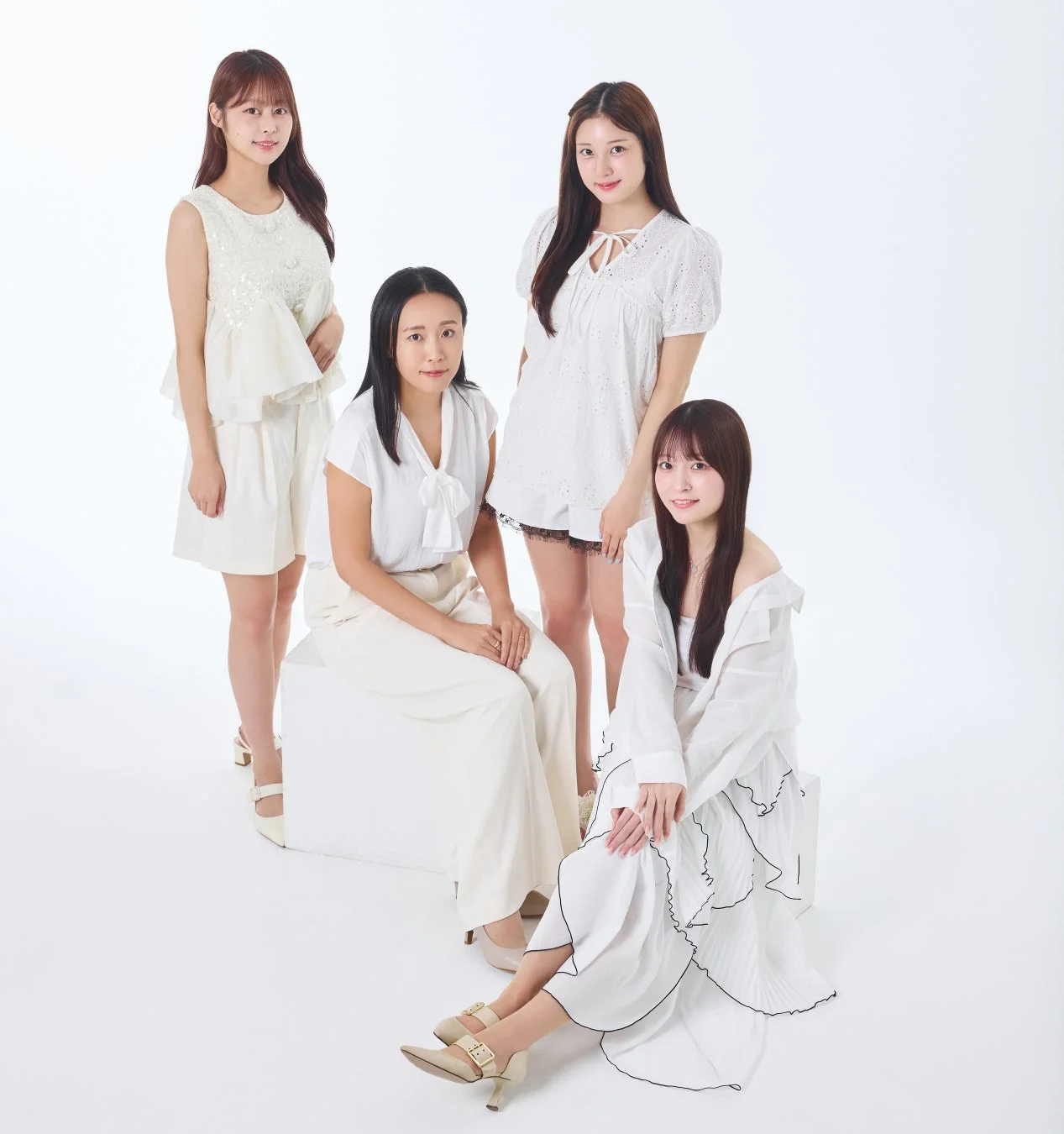 白い衣装を身につけた4人の女性が白い背景のスタジオでポーズをとっている集合写真です。