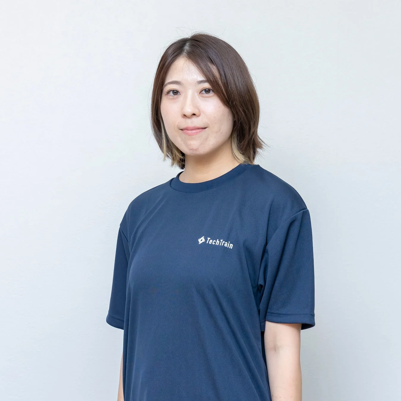 TechTrainのロゴ入りTシャツを着たショートヘアの女性