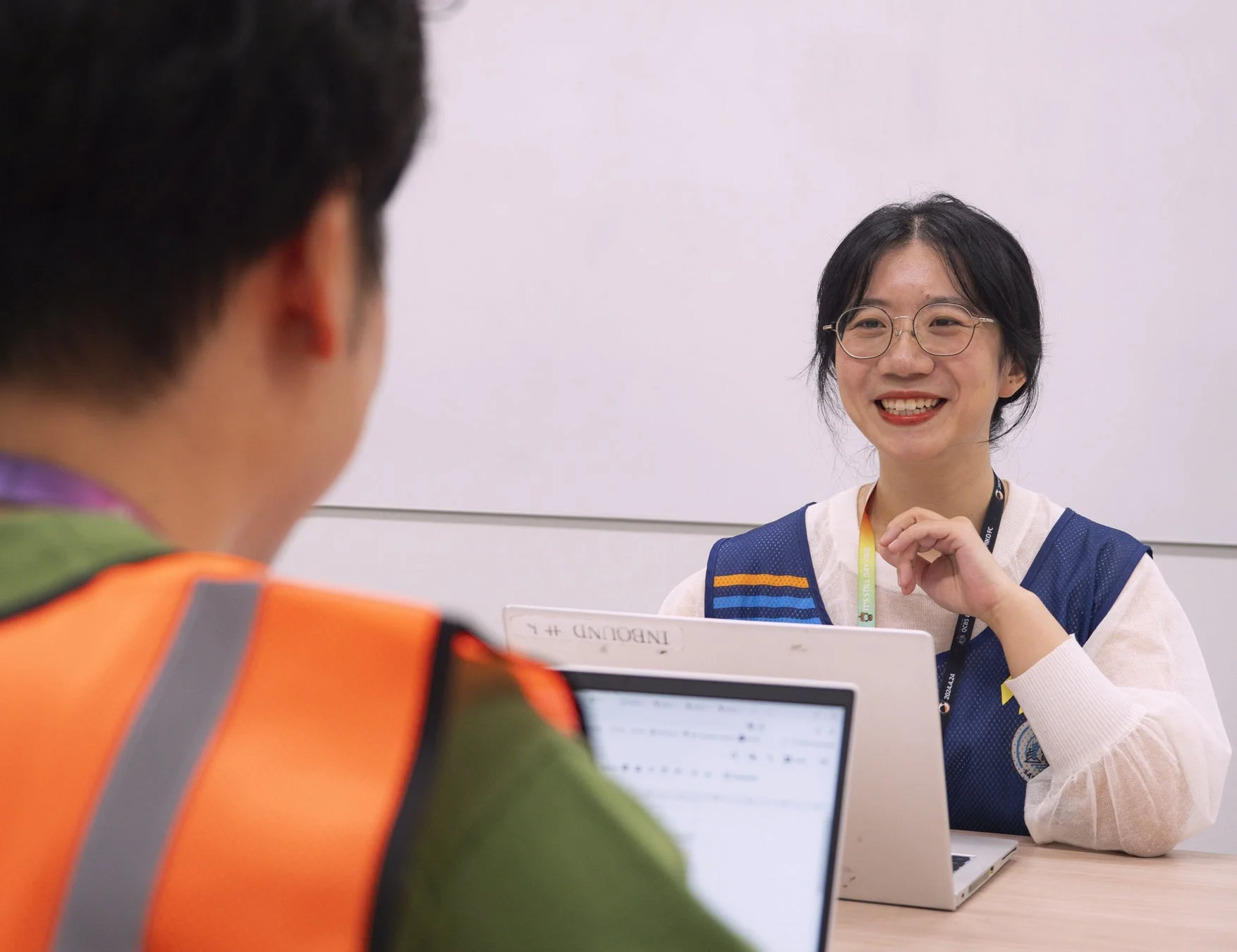 オフィスで女性がノートパソコンを前に笑顔で話している様子